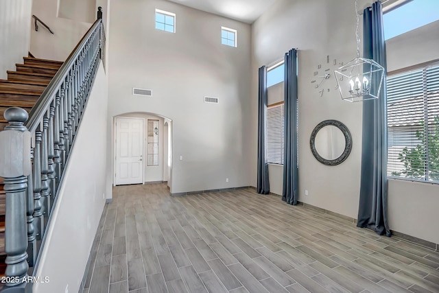 11936 W Alvarado Rd, Avondale, AZ 85392 - foyer featuring arched walkways, a chandelier, a towering ceiling, light wood-style floors, and stairway