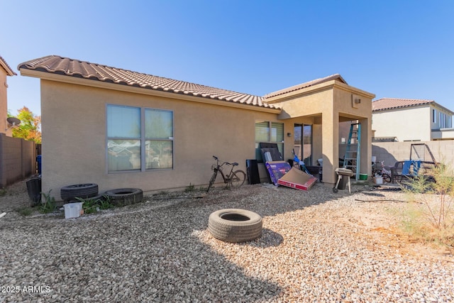 back of property featuring a tile roof, fence, and stucco siding