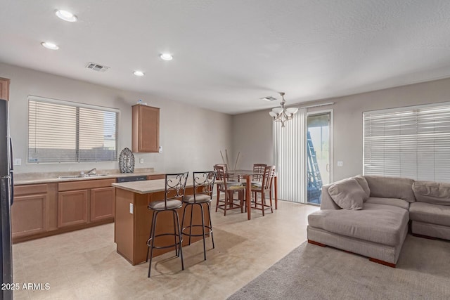 kitchen with visible vents, a kitchen island, open floor plan, light countertops, and a kitchen bar