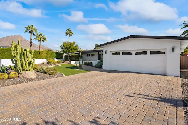 ranch-style home with a garage, decorative driveway, and a mountain view