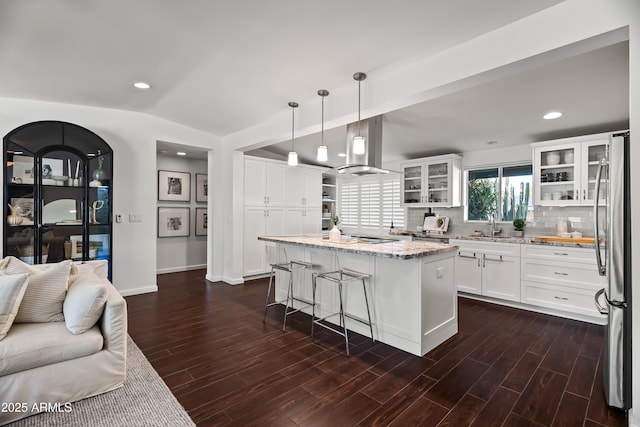 kitchen with white cabinetry, island range hood, stainless steel fridge, a kitchen island, and pendant lighting