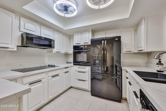 kitchen with a sink, black appliances, a ceiling fan, and a raised ceiling