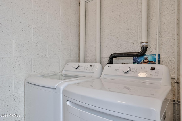 laundry area featuring washing machine and dryer, laundry area, and concrete block wall