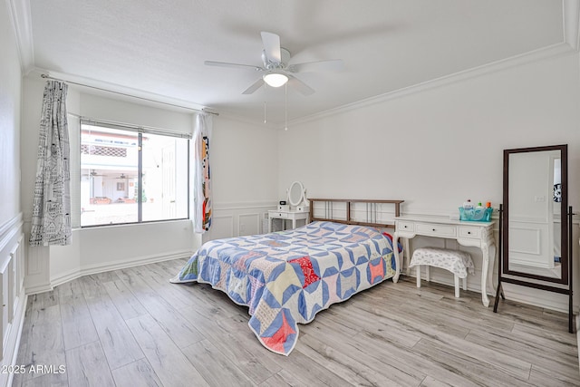 bedroom with a wainscoted wall, a ceiling fan, wood finished floors, and crown molding