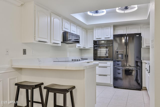 kitchen featuring white cabinetry, a kitchen bar, a peninsula, light tile patterned floors, and black appliances