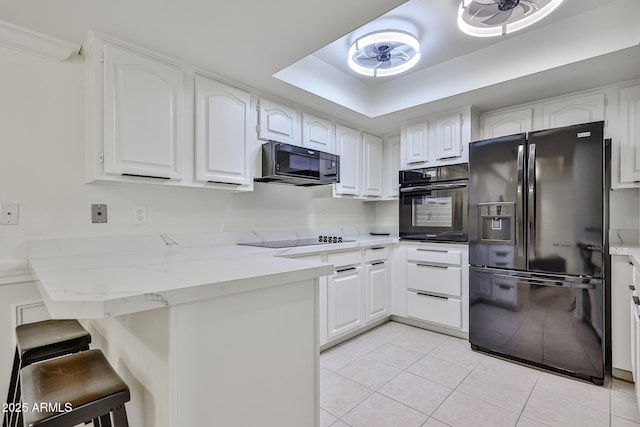 kitchen featuring white cabinetry, black appliances, a kitchen breakfast bar, and a peninsula