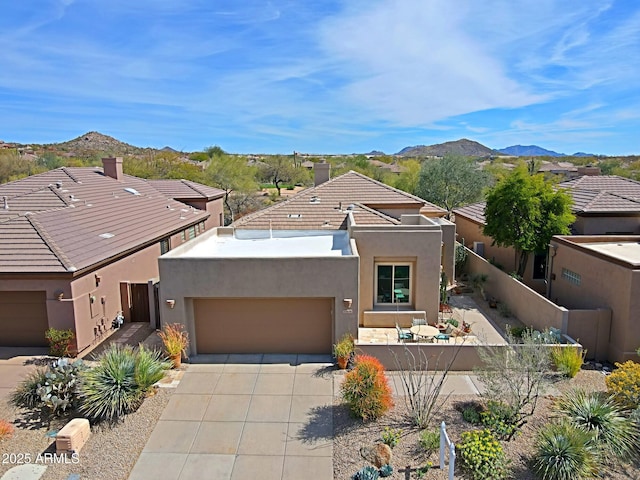 view of front of property featuring concrete driveway, stucco siding, fence, an attached garage, and a mountain view
