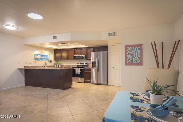 2925 E Dragoon Ave, Mesa, AZ 85204 - kitchen featuring stainless steel appliances, a peninsula, dark brown cabinetry, light tile patterned flooring, and a tray ceiling