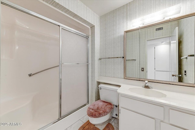 bathroom with tile patterned flooring, vanity, a shower with shower door, and toilet