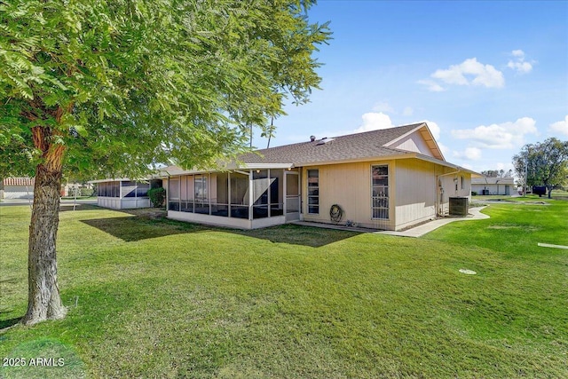 back of house featuring central AC, a sunroom, and a lawn