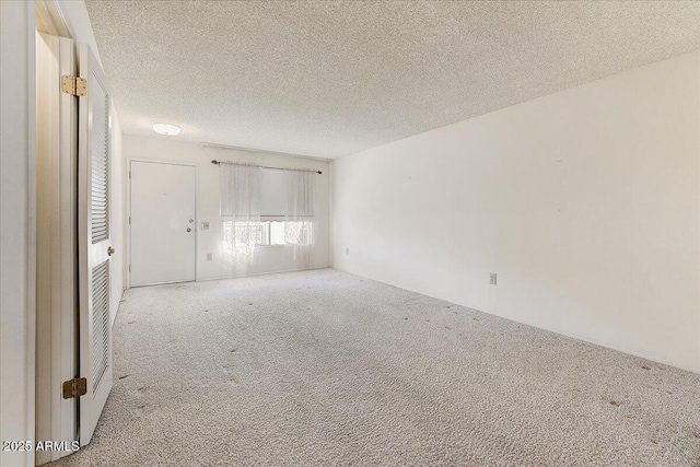 empty room with light colored carpet and a textured ceiling