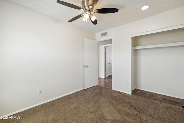 unfurnished bedroom with visible vents, a textured ceiling, a closet, carpet floors, and baseboards