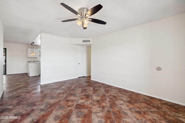 unfurnished living room featuring a textured ceiling, baseboards, visible vents, and ceiling fan