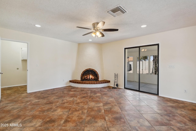 unfurnished living room featuring a brick fireplace, baseboards, visible vents, and ceiling fan