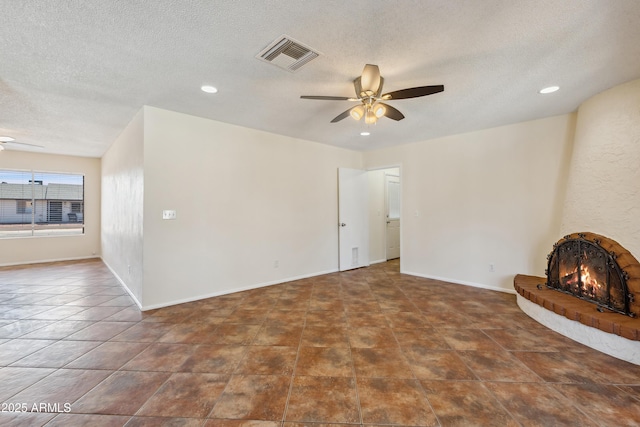 unfurnished living room featuring visible vents, a textured ceiling, baseboards, a brick fireplace, and ceiling fan