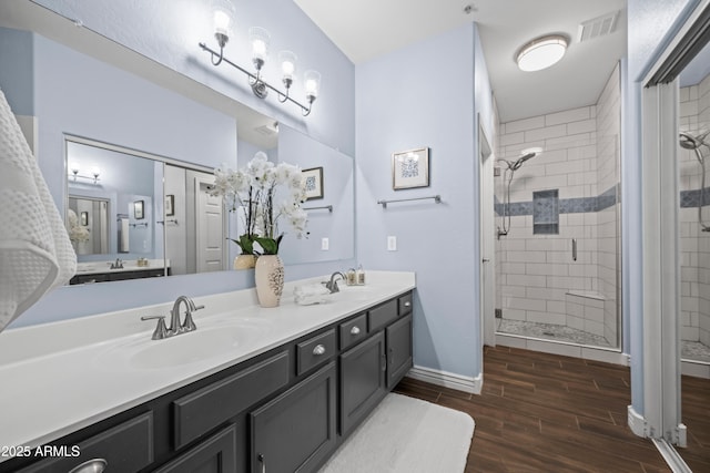 full bath with visible vents, wood tiled floor, double vanity, a stall shower, and a sink