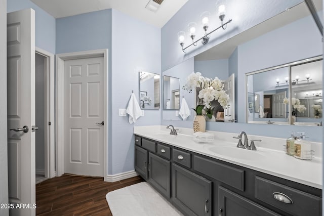 bathroom featuring a sink, visible vents, double vanity, and wood tiled floor