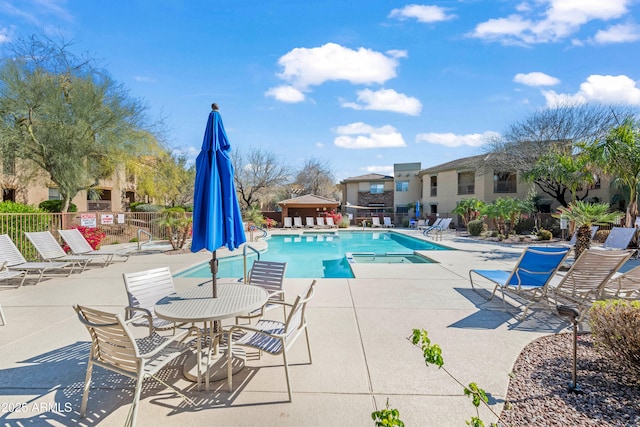 community pool with a patio area and fence