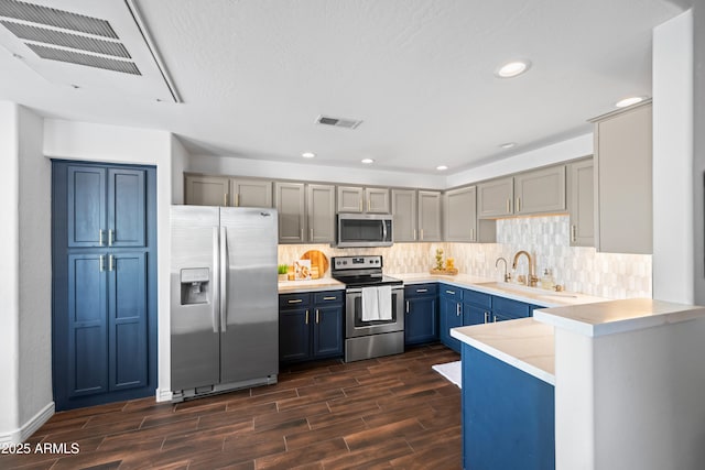 kitchen with visible vents, light countertops, decorative backsplash, appliances with stainless steel finishes, and a sink