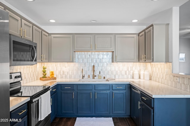 kitchen with stainless steel appliances, light countertops, wood finish floors, and a sink