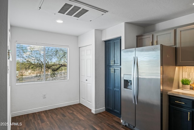 kitchen with blue cabinets, visible vents, dark wood finished floors, stainless steel fridge, and baseboards