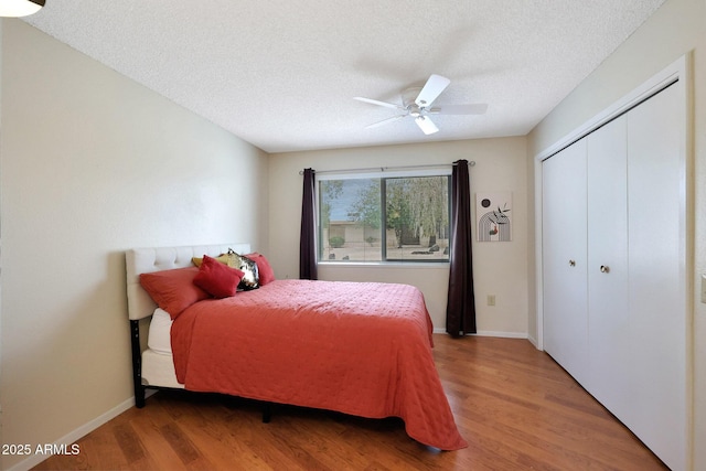 bedroom featuring a closet, a textured ceiling, light wood-type flooring, and baseboards