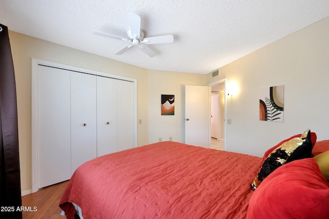 bedroom with visible vents, ceiling fan, light wood-type flooring, a closet, and a textured ceiling