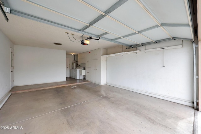 garage featuring visible vents, a garage door opener, and independent washer and dryer