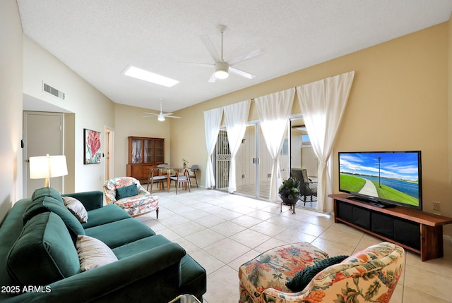 living room with visible vents, a ceiling fan, a textured ceiling, light tile patterned floors, and vaulted ceiling