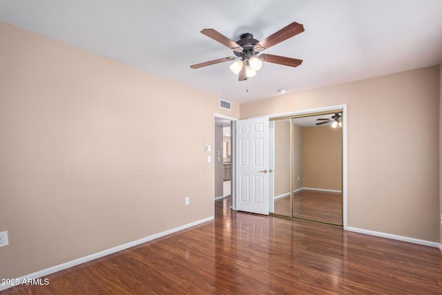 unfurnished bedroom with dark wood-type flooring, a closet, and ceiling fan