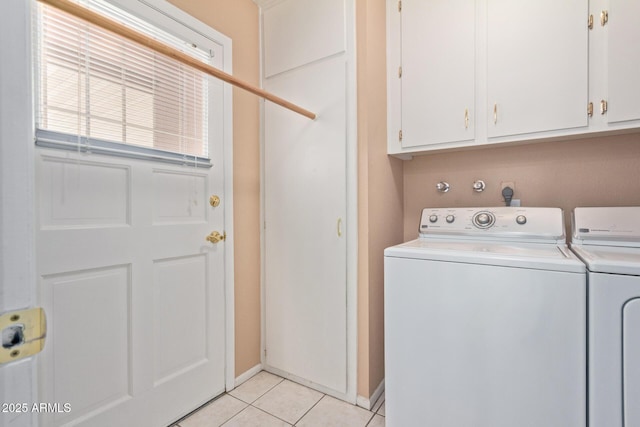 clothes washing area featuring light tile patterned flooring, cabinets, and washer and dryer