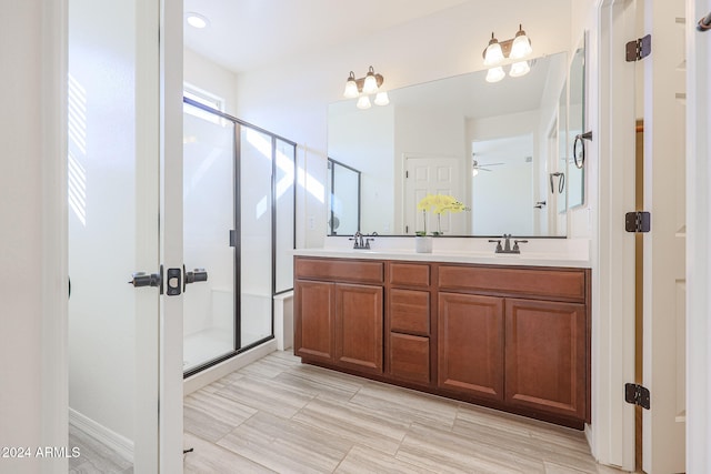 bathroom featuring ceiling fan, a shower with shower door, and vanity