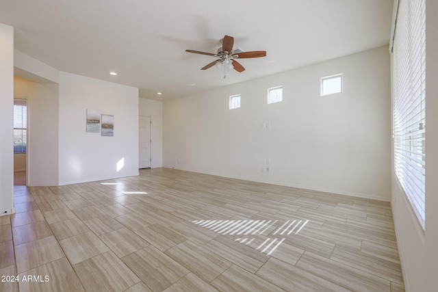 spare room featuring a wealth of natural light, ceiling fan, and light hardwood / wood-style flooring