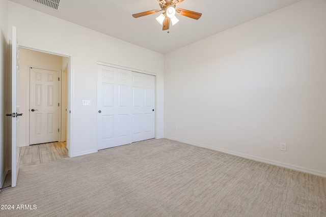 unfurnished bedroom featuring light colored carpet, ceiling fan, and a closet