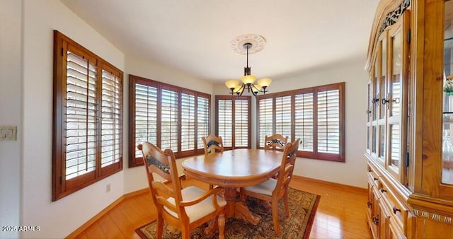 dining room with baseboards, light wood-type flooring, and an inviting chandelier