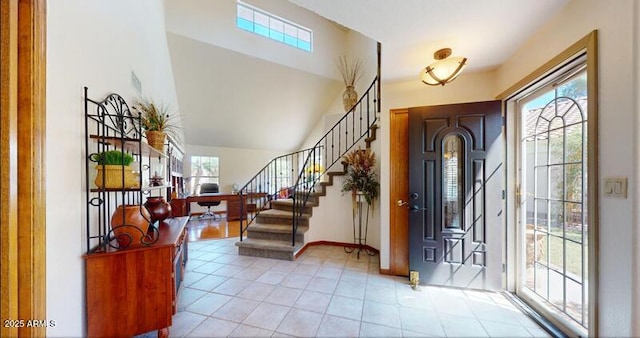 foyer featuring light tile patterned floors, baseboards, stairs, and vaulted ceiling