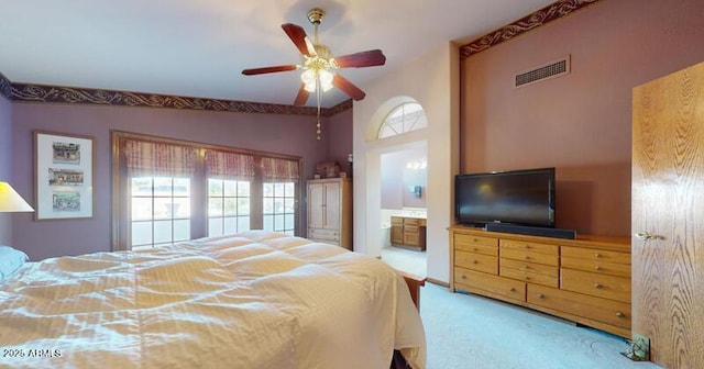 carpeted bedroom with lofted ceiling, visible vents, ensuite bathroom, and ceiling fan