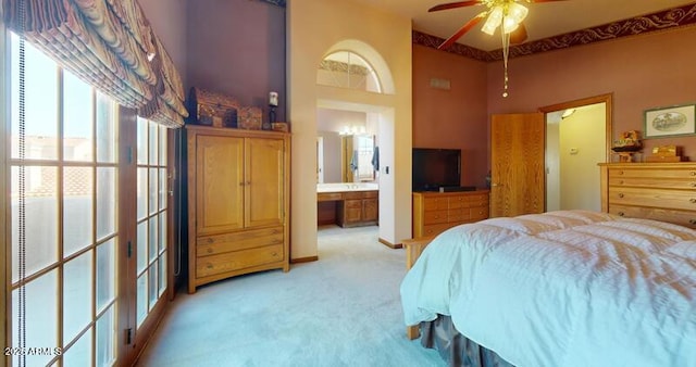 bedroom with light colored carpet, ceiling fan, and ensuite bathroom