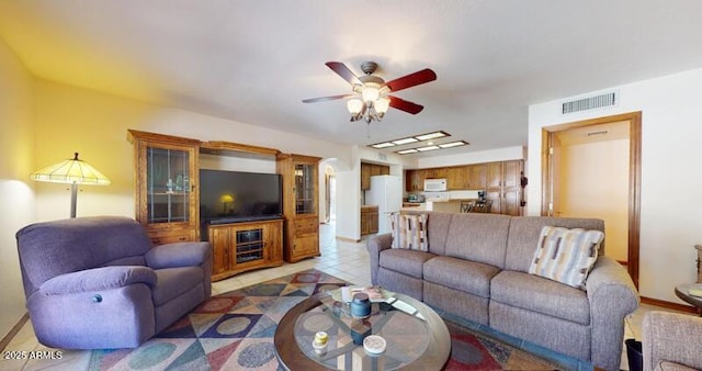 living area featuring light tile patterned floors, visible vents, baseboards, and a ceiling fan