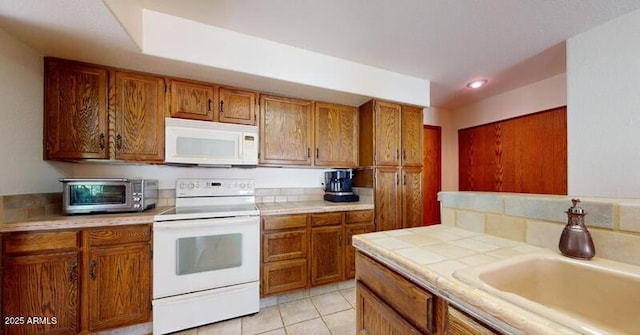 kitchen featuring a sink, white appliances, brown cabinets, and a toaster