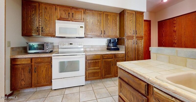 kitchen featuring tile counters, a toaster, light tile patterned floors, brown cabinetry, and white appliances