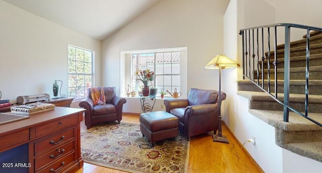 sitting room featuring stairs, light wood-style flooring, and high vaulted ceiling