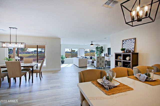 dining space with hardwood / wood-style floors and ceiling fan with notable chandelier