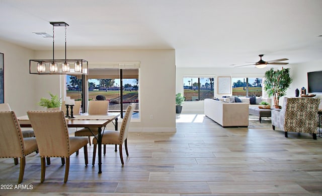 dining area featuring wood-type flooring and ceiling fan with notable chandelier