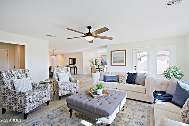 living room featuring light hardwood / wood-style floors and ceiling fan with notable chandelier