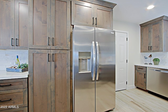 kitchen with decorative backsplash, stainless steel appliances, and light hardwood / wood-style floors