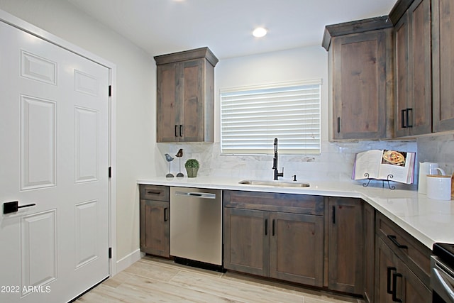 kitchen featuring appliances with stainless steel finishes, sink, backsplash, dark brown cabinets, and light hardwood / wood-style flooring