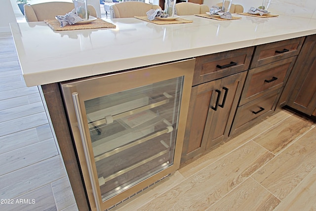 interior details featuring light hardwood / wood-style flooring, dark brown cabinetry, and beverage cooler