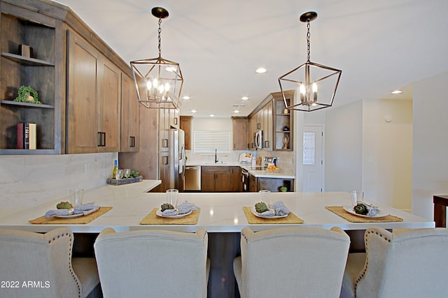 kitchen featuring stainless steel appliances, tasteful backsplash, a kitchen breakfast bar, and hanging light fixtures