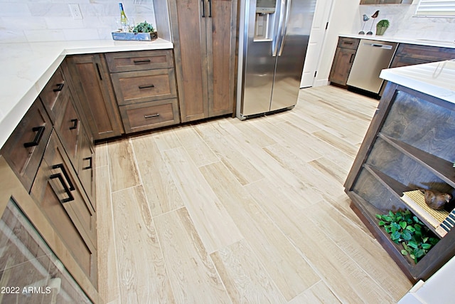 kitchen featuring light hardwood / wood-style flooring, dark brown cabinetry, stainless steel appliances, and backsplash